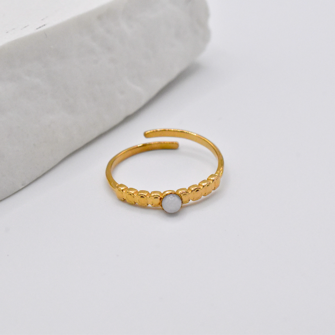 Bague modèle Dotty en or pierre blanche posée près d'un support