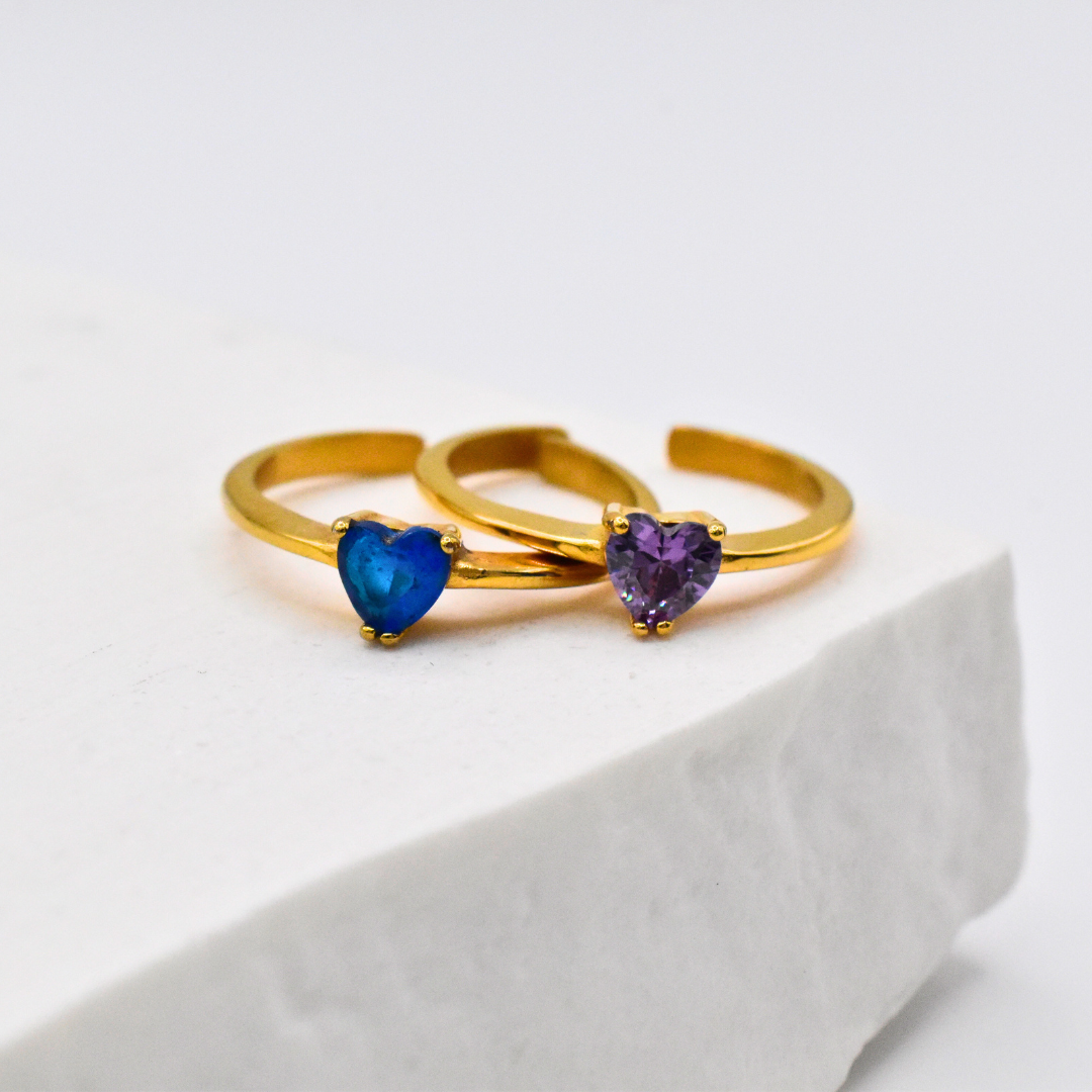 Bagues modèle heart ring en or coeur bleu et coeur violet entrelacées sur support