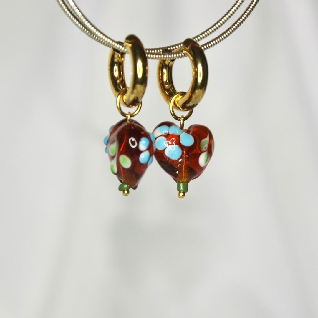 Boucles d'oreilles modèle Feelings Earrings en or avec pendant coeur en pierre rouge sur présentoir