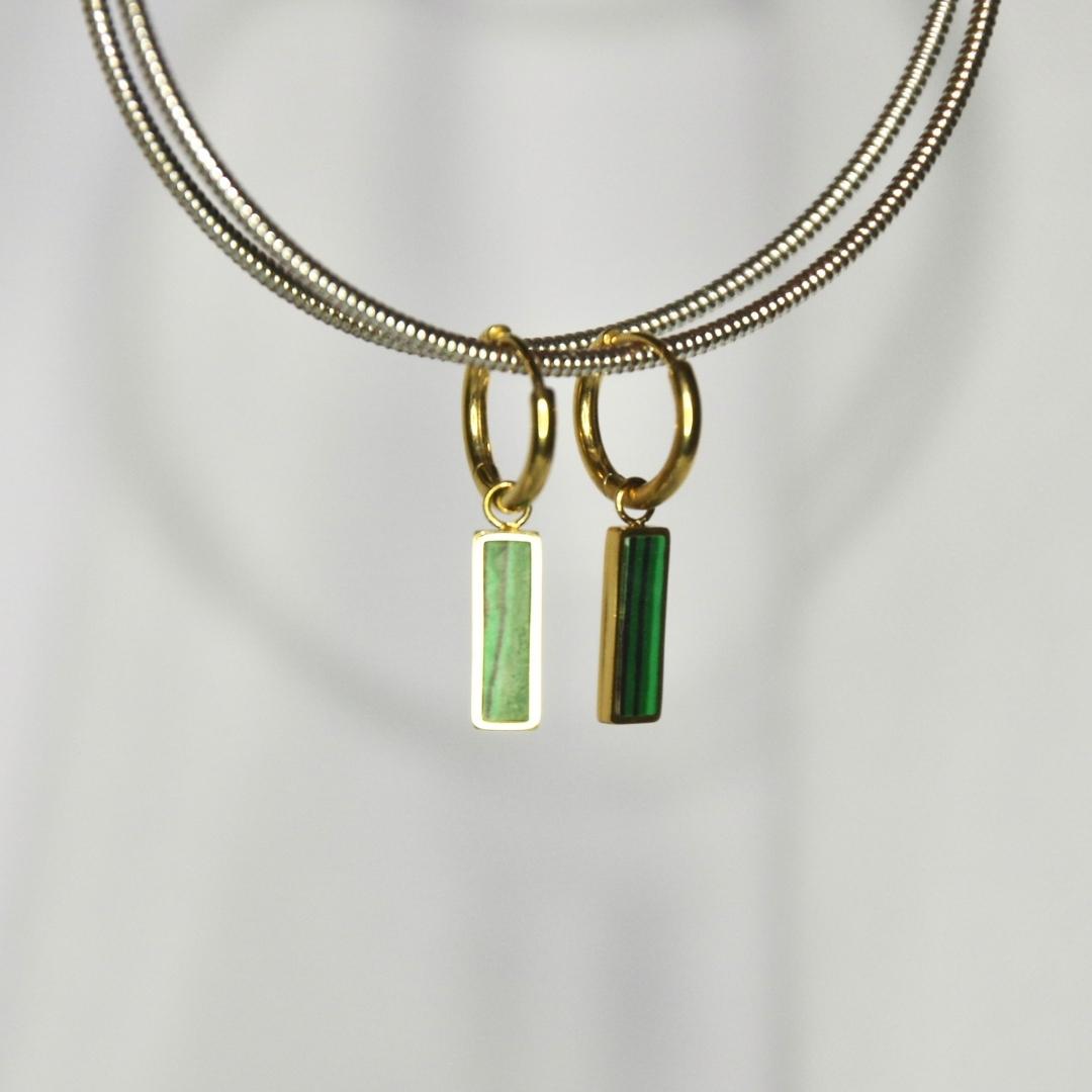 Boucles d'oreilles modèle Loki Earrings en or avec pendant barre en pierre verte sur présentoir
