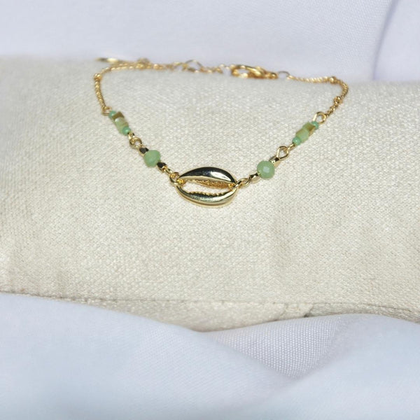 Bracelet modèle Tide Bracelet en or avec coquillage et pierres vertes sur présentoir