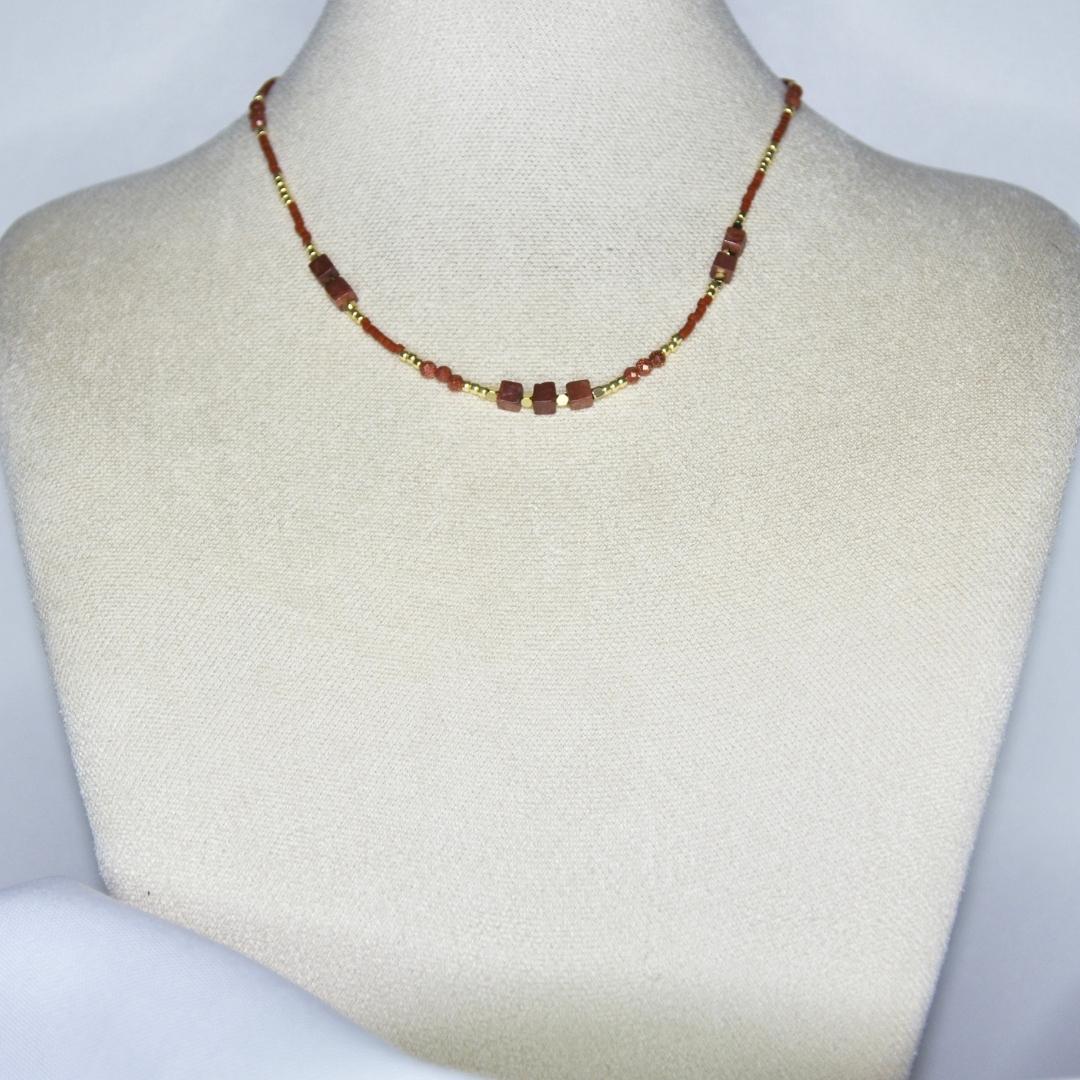 Collier modèle Isle Necklace avec perles dorées et marrons sur présentoir