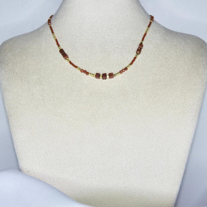 Collier modèle Isle Necklace avec perles dorées et marrons sur présentoir