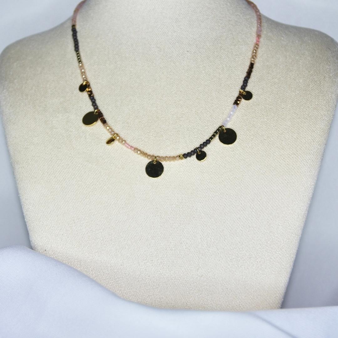 Collier modèle Topping Necklace en perles roses, blanches et noires orné de pendants ronds et dorés sur présentoir