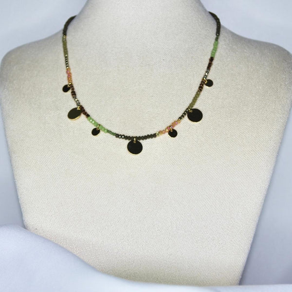Collier modèle Topping Necklace en perles vertes, roses et noires orné de pendants ronds et dorés sur présentoir